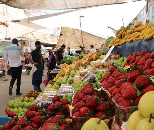 Rengarenk Semt Pazarları Şehrin Kalbi Semt pazarları, şehir hayatının vazgeçilmez parçalarından biridir. Hem ekonomik alışveriş imkânı sunmaları hem de toplumsal bir buluşma noktası olmalarıyla ön plana çıkarlar. Her hafta belirli günlerde kurulan bu pazarlar, şehrin farklı bölgelerindeki insanları bir araya getirir. Tezgâhlarda yer alan taze sebzeler, meyveler, baharatlar ve yerel ürünler, hem damak zevkine hitap eder hem de bölgesel kültürün yaşatılmasına katkı sağlar. Konulu bir haber görseli.